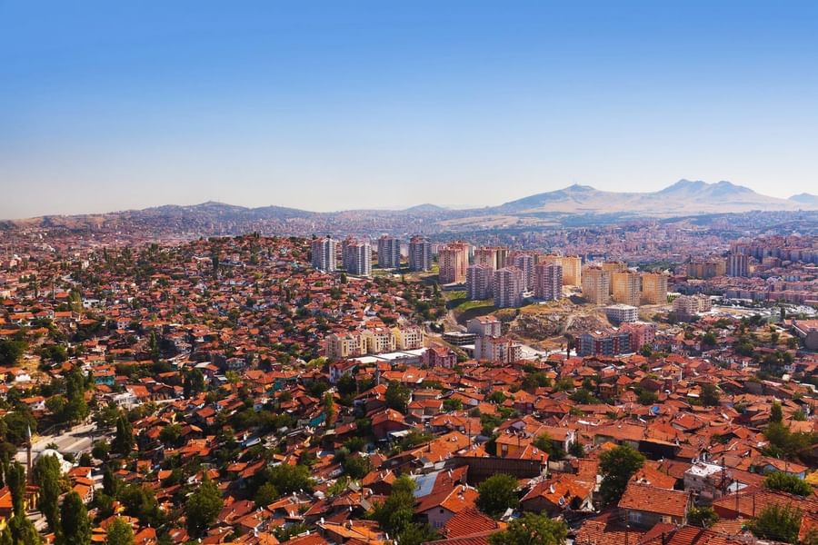 Red rooftops by modern high-rises surrounding a hilly landscape near Warwick Ankara