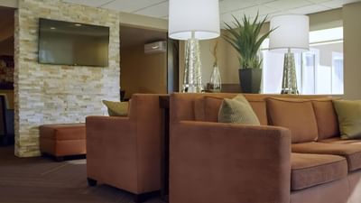 Modern lobby lounge at Moab Valley Inn with a textured stone wall, TV, plush sofa with stylish lamps