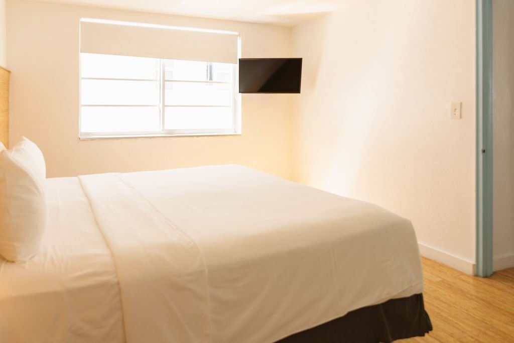 A wide view of a hotel room with a king-size bed, flat-screen TV, and window