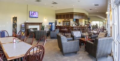 Armchairs by a wooden fireplace under ceiling lights at Rodd Brudenell River Resort, one of the premier places to stay in PEI