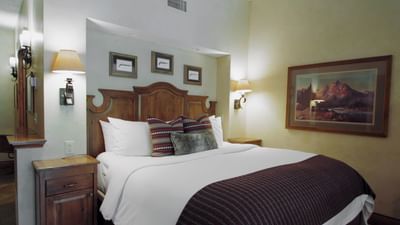 Bed with side table and wall-mounted artwork in Governor's Suite at Hotel Park City Autograph Collection