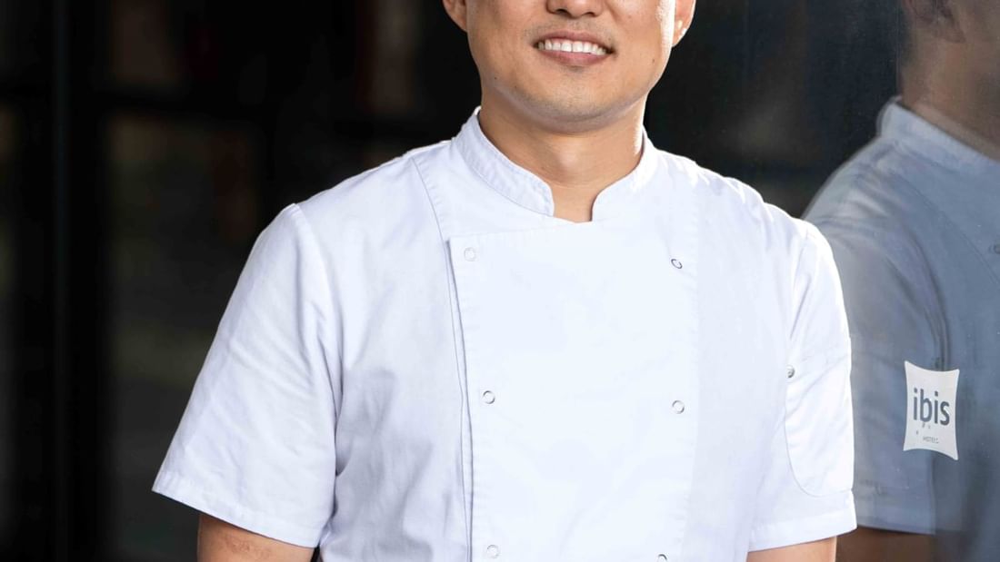 Portrait of a chef smiling confidently in a white uniform at Ibis Adelaide