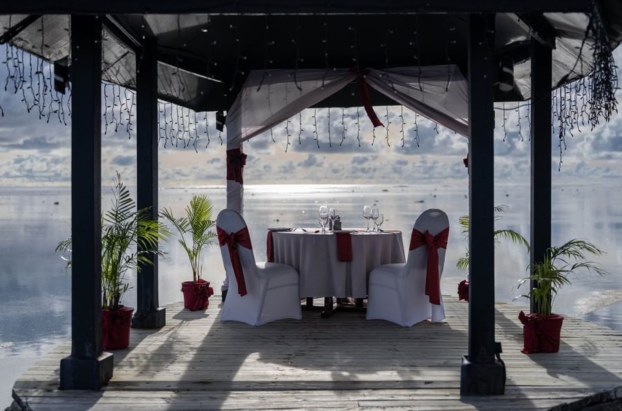 Set table with white chairs by a draped gazebo under string lights at Warwick Fiji Resort and Spa