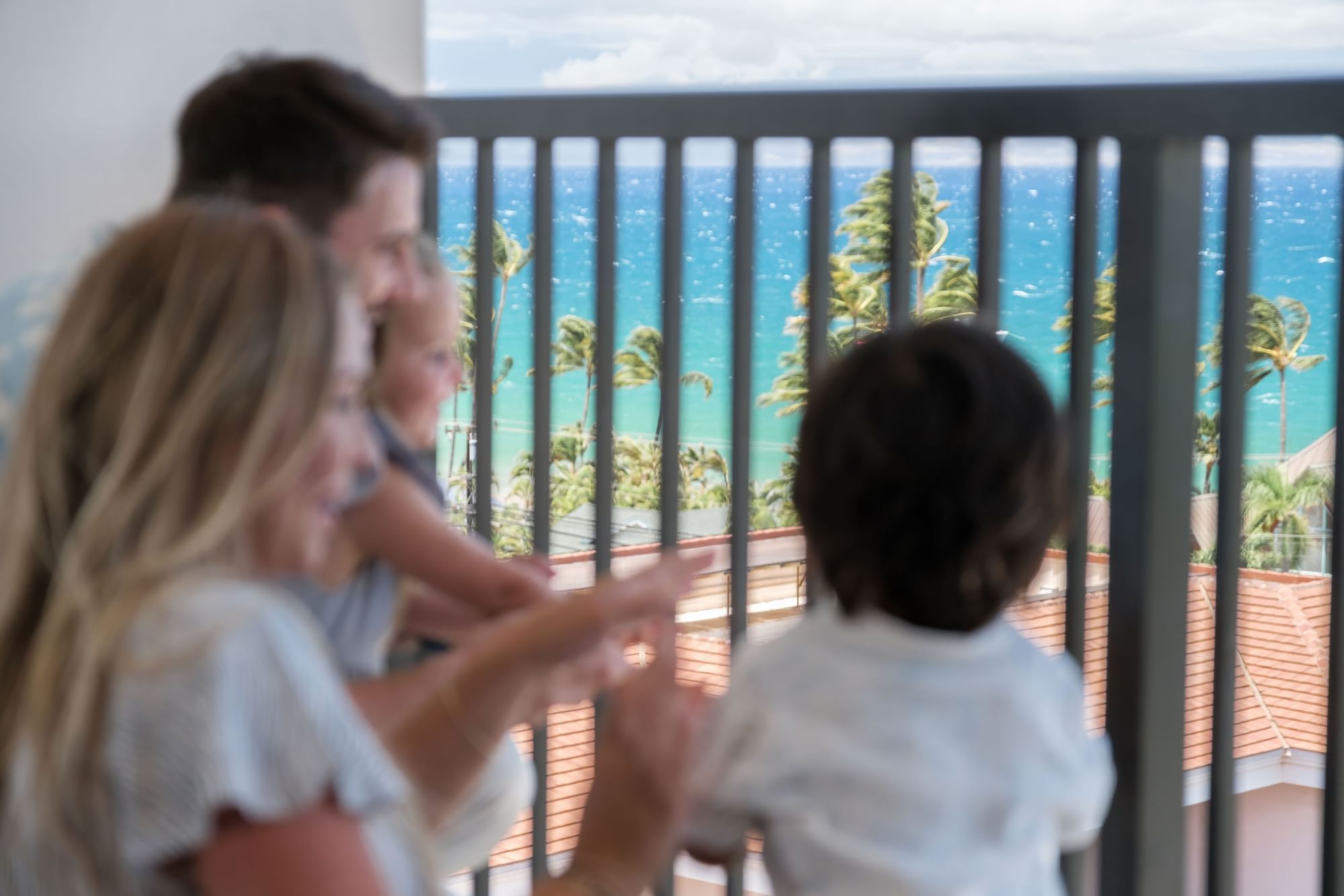 A family of four enjoys the ocean view from a balcony.
