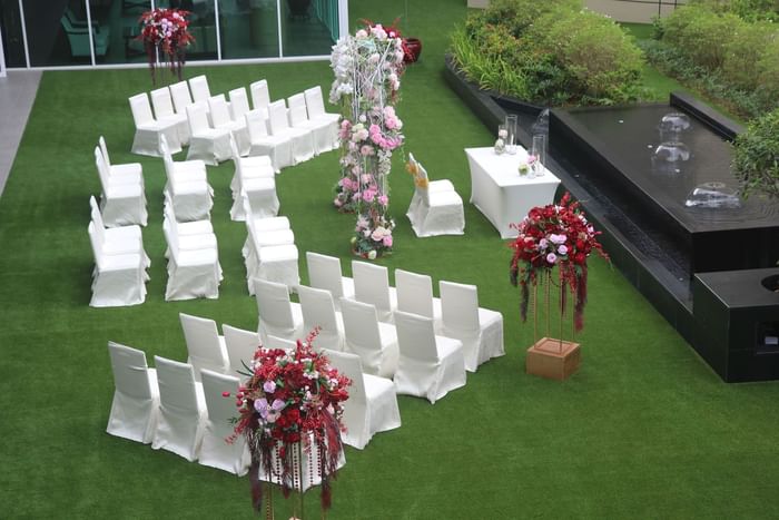 Outdoor wedding or event setup on a green lawn at One World Hotel, featuring white chairs and floral decor