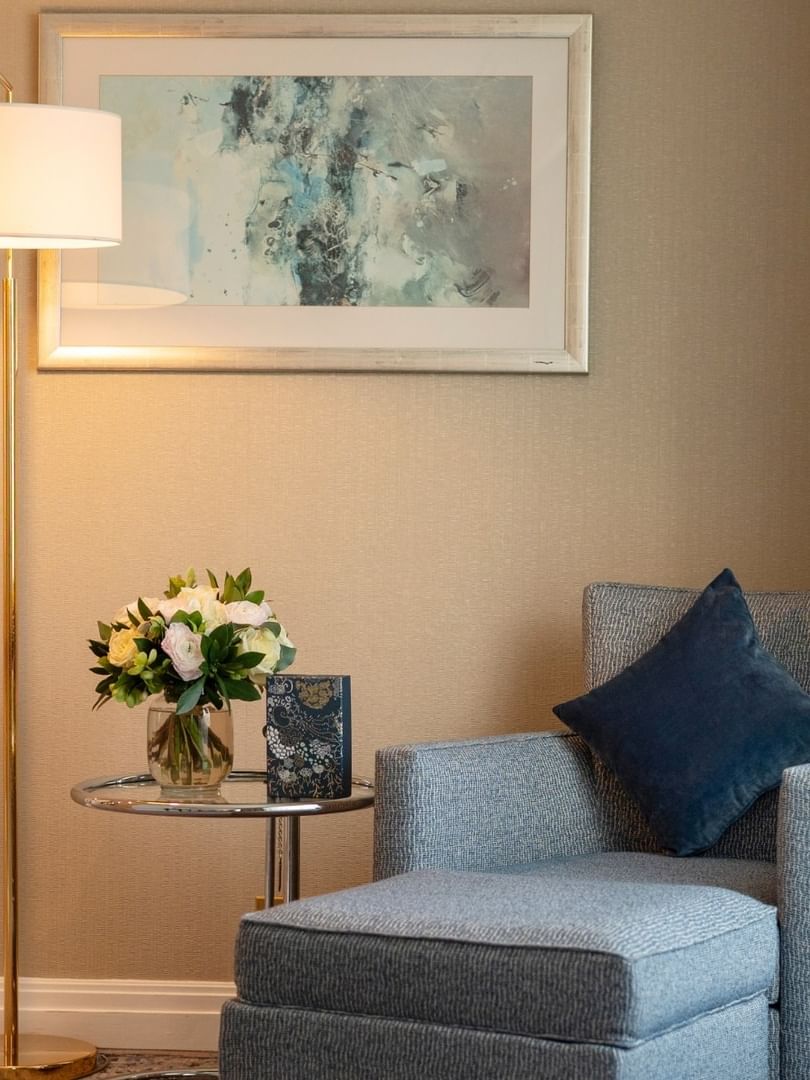 Blue ottoman and chair by a glass table under abstract wall art in The Champs-Élysées Suite at Warwick Paris Champs Elysées