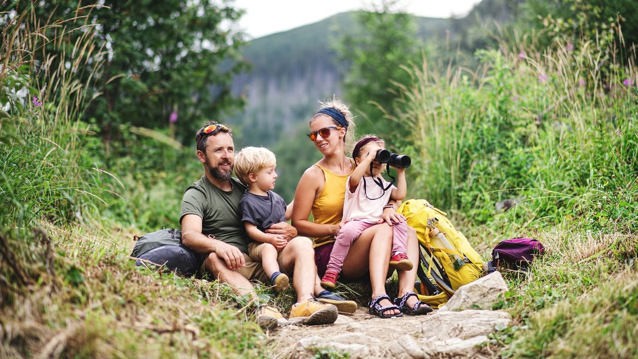 Family of four with backpacks on a hiking trail at Whitecourt Sandhills.