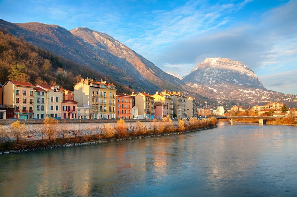 Colorful riverside buildings by the Isère River with mountain views near ResidHotel Grenoble Grenette