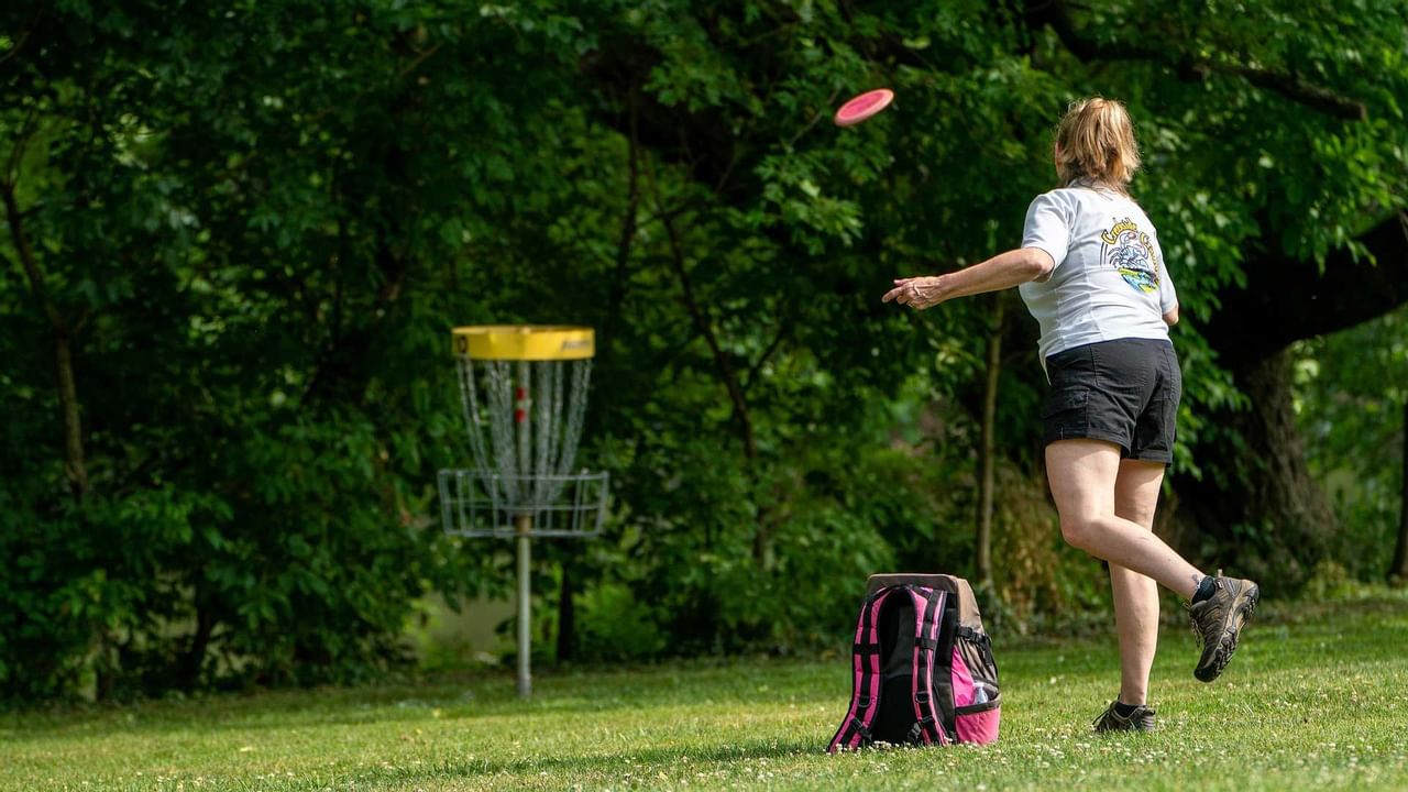 Woman throwing a disc to the disc golf target