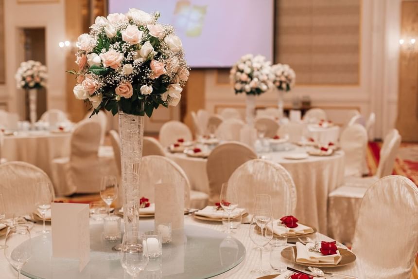 Wedding reception tables adorned with tall floral centerpieces, fine dining setups, and soft lighting at Park Hyatt Saigon