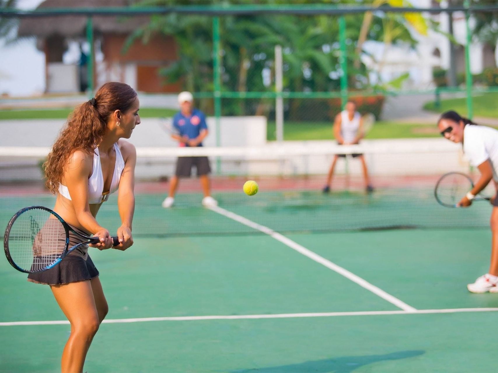 Mujer jugando tenis en cancha verde en Guadalajara Plaza Hoteles & Suites, hoteles de lujo en Puerto Vallarta