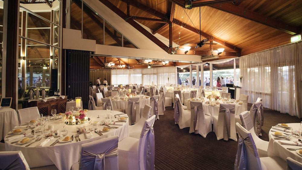 Banquets set up with floral centerpieces and soft lighting in Lily’s on the Lagoon at Novotel Sunshine Coast Resort
