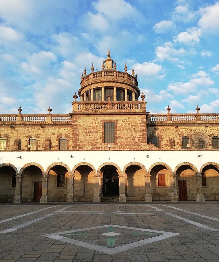 Stone arches by a large courtyard under a domed tower in the sun at Camino Real Pedregal Mexico