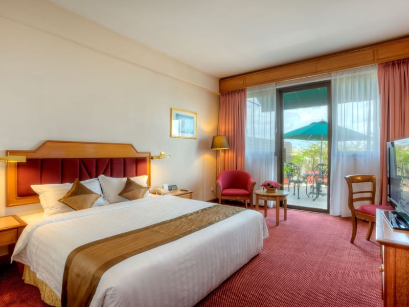 Deluxe balcony room at Sunway Hotel Phnom Penh with a king-sized bed, red carpet, and a private balcony patio with seating