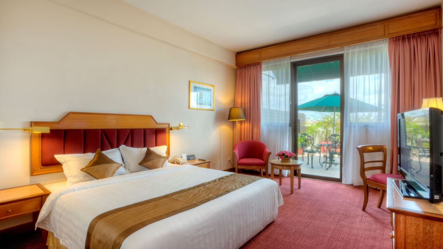 Deluxe balcony room at Sunway Hotel Phnom Penh with a king-sized bed, red carpet, and a private balcony patio with seating