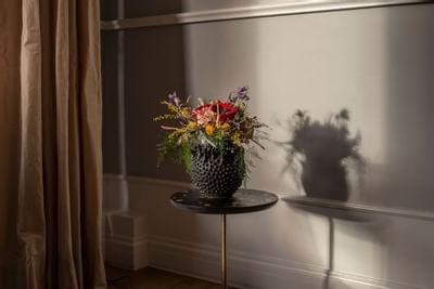 A flower vase on a stool by a curtain at The Sparrow Hotel