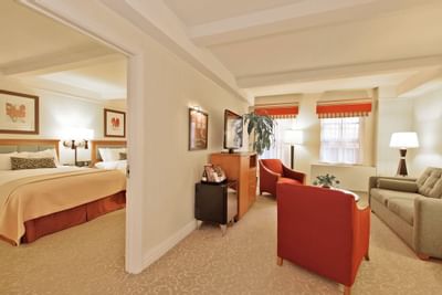 Suite with two large beds, sofa, two armchairs, and a window with curtains.