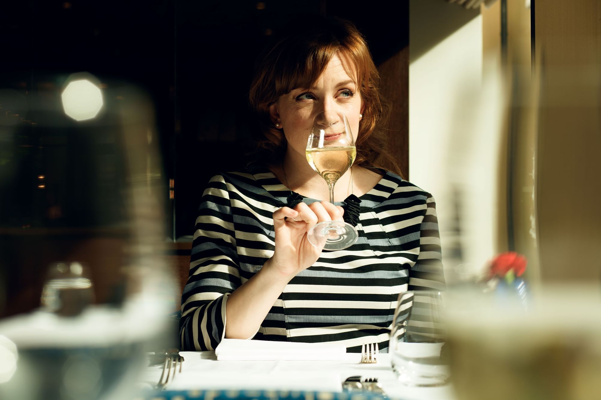 Woman in a striped shirt enjoying a glass of white wine in a restaurant at The Londoner