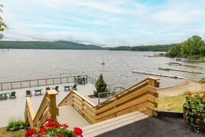 Wooden deck with steps overlooking lake with a forested hill in The Lodge at Schroon Lake