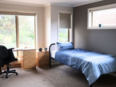 Bedroom with a single bed, desk, chair, and two windows at La Trobe University Regional Housing – Melton.