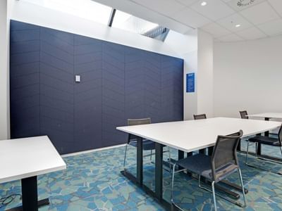 Modern study room with white tables, mesh chairs, and blue patterned carpet at UniLodge Auckland Central.