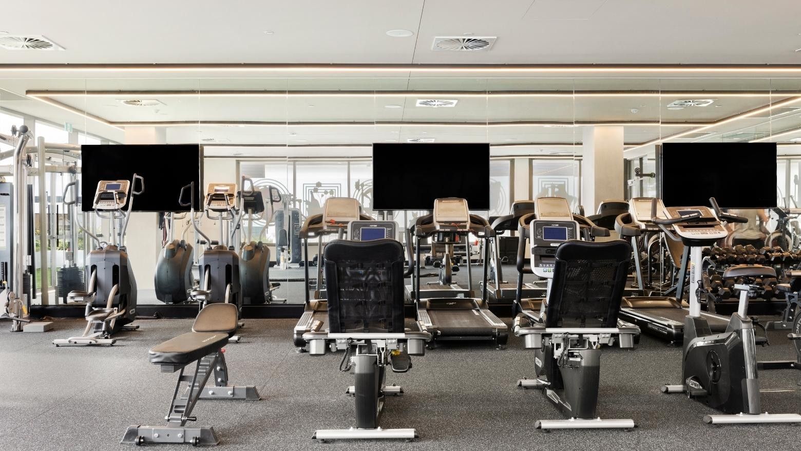 Modern gym with various exercise machines, including treadmills, stationary bikes, and weight equipment.