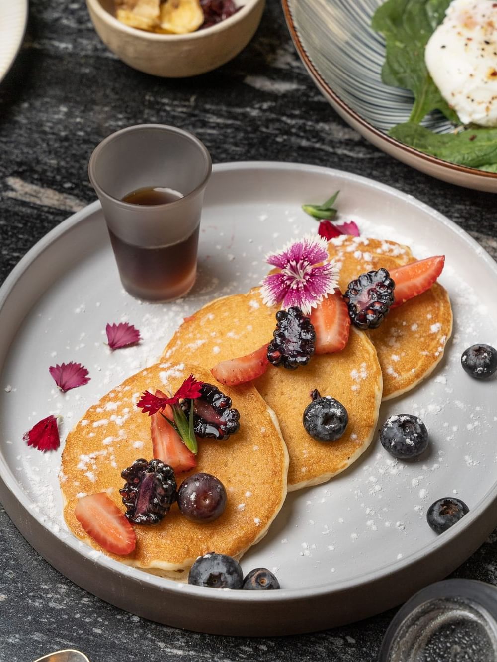 Close-up of breakfast pancakes served with syrup & berries at Azimuth Barcelona