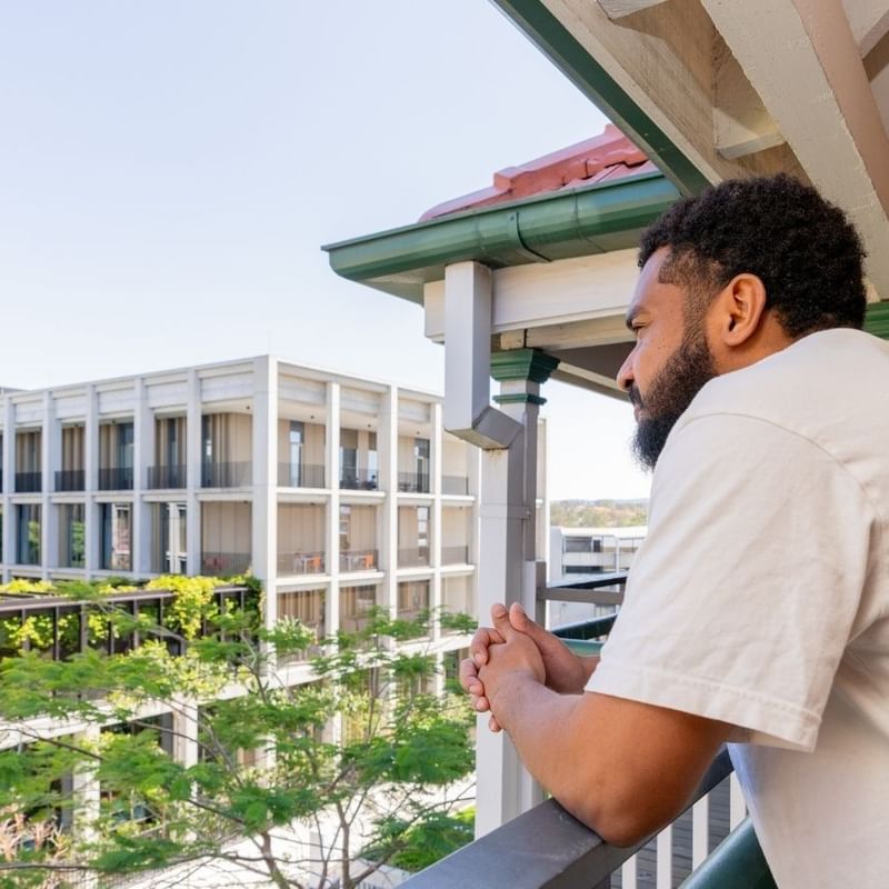 Student looking out from a balcony.