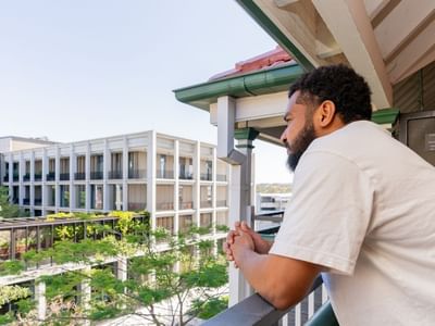 Student looking out from a balcony.