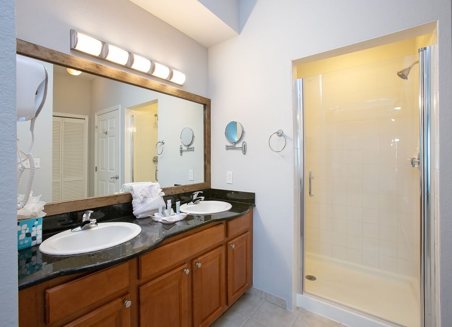 A clean bathroom with a double vanity, large mirror, and separate shower.