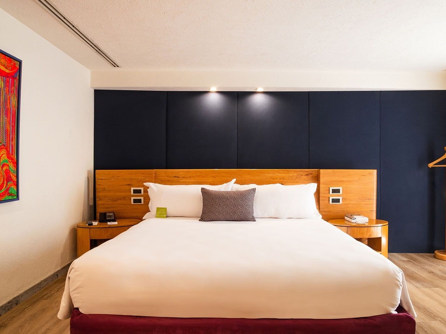King Camichin Suite bed with a dark blue headboard wall and vibrant wall artwork at Camino Real Guadalajara