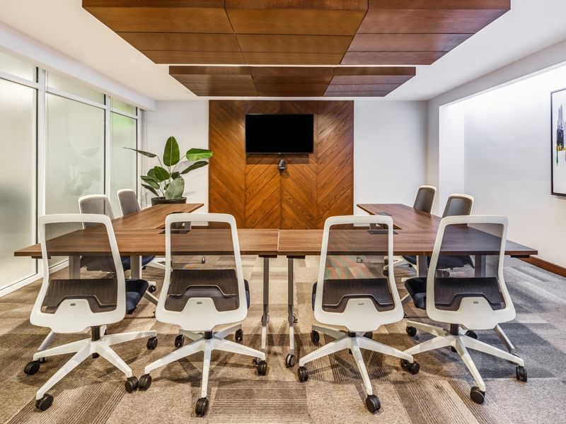 Business center 2 with white rolling chairs, a wooden accent wall, and a flat-screen TV for meetings at Sunvivia Mazatlán