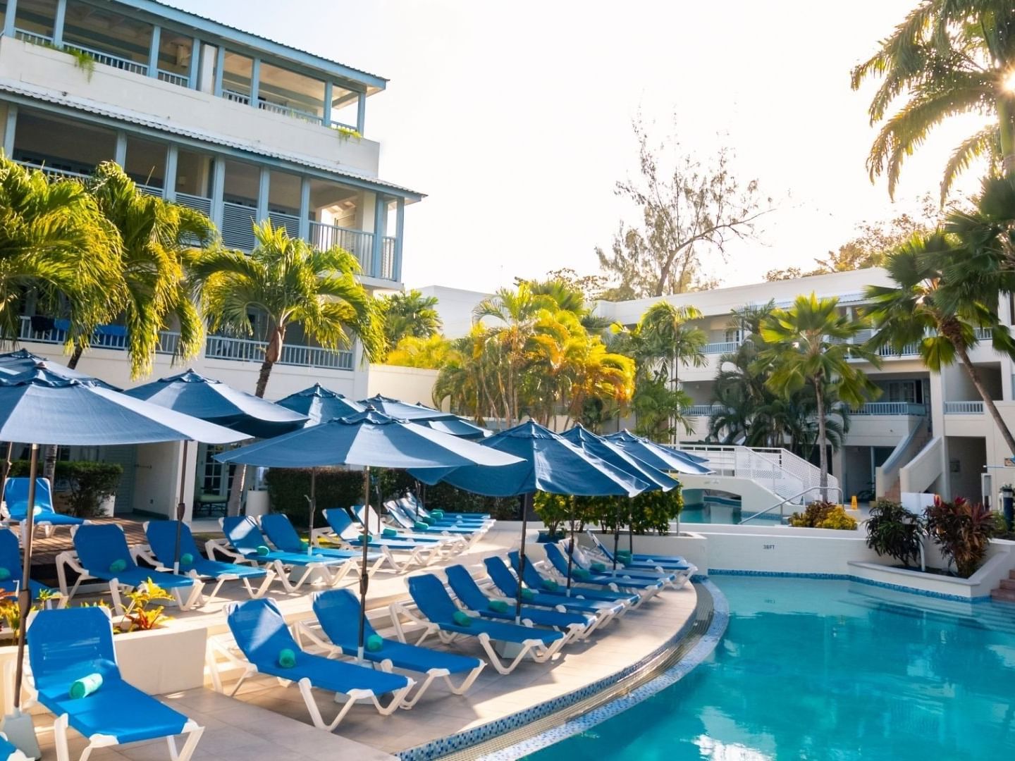 Row of blue lounge chairs with umbrellas by pool at Savannah Beach Hotel.