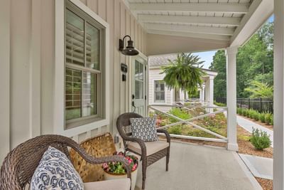 Cozy porch with woven chairs framed by greenery and a charming cottage path by Cottages at Laurel Brooke