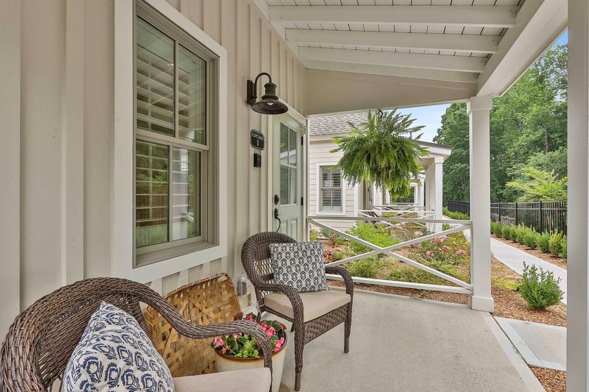 Cozy porch with woven chairs framed by greenery and a charming cottage path by Cottages at Laurel Brooke