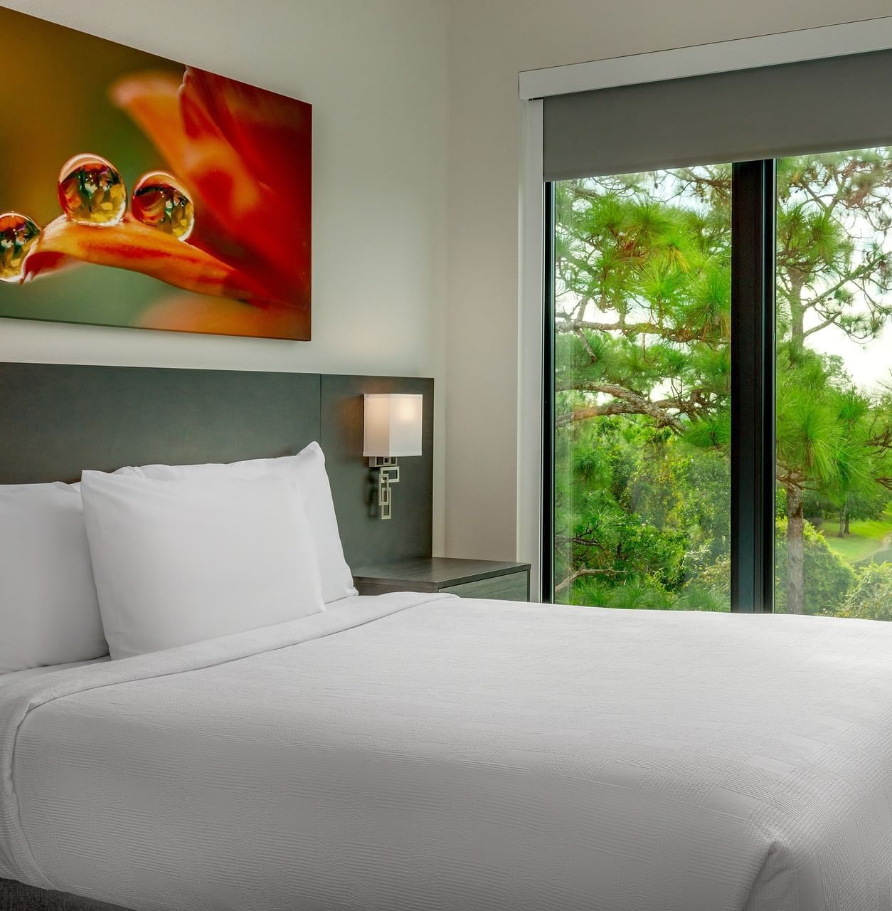 Terraces Two Bedroom Suite with bed and greenery view through window at The Grove Resort & Water Park