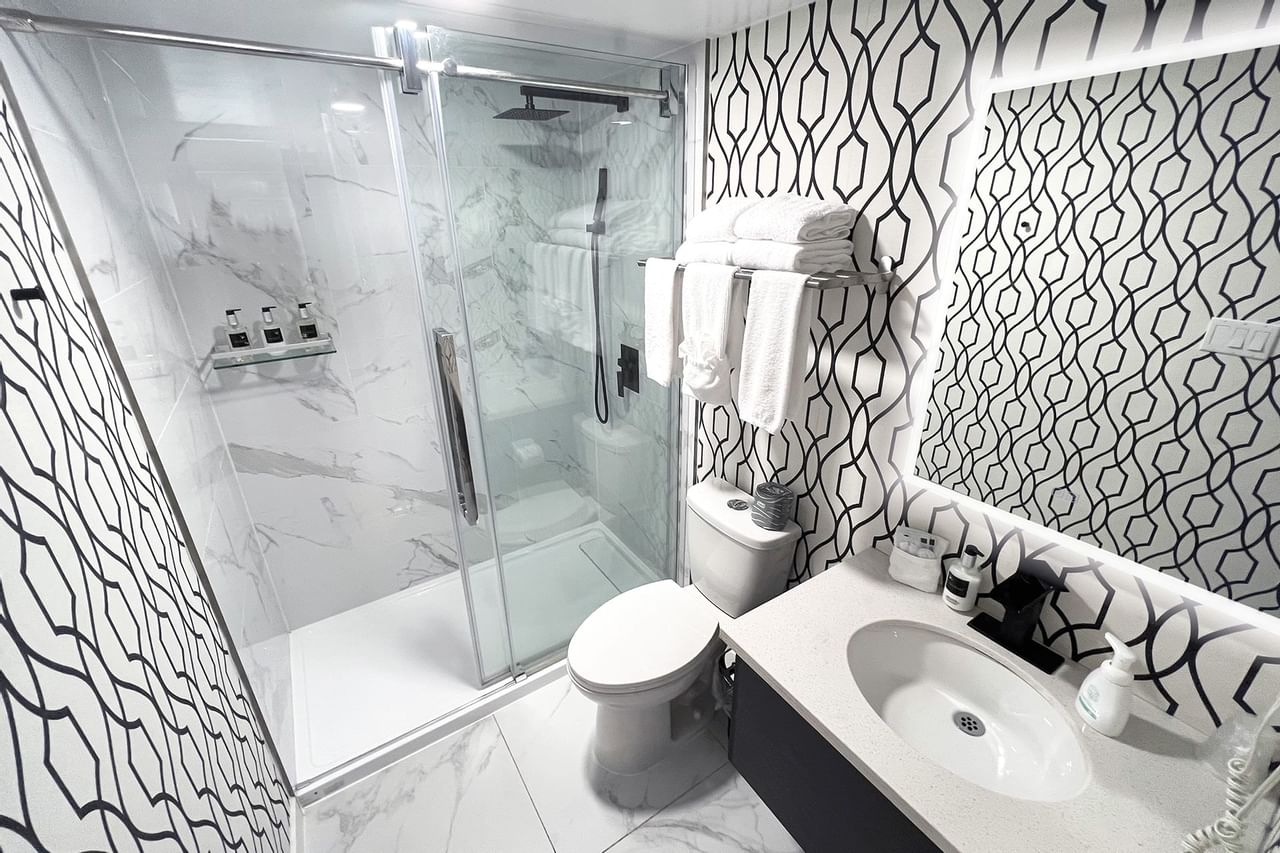 Bathroom with towels, toilet, mirror, shower and sink