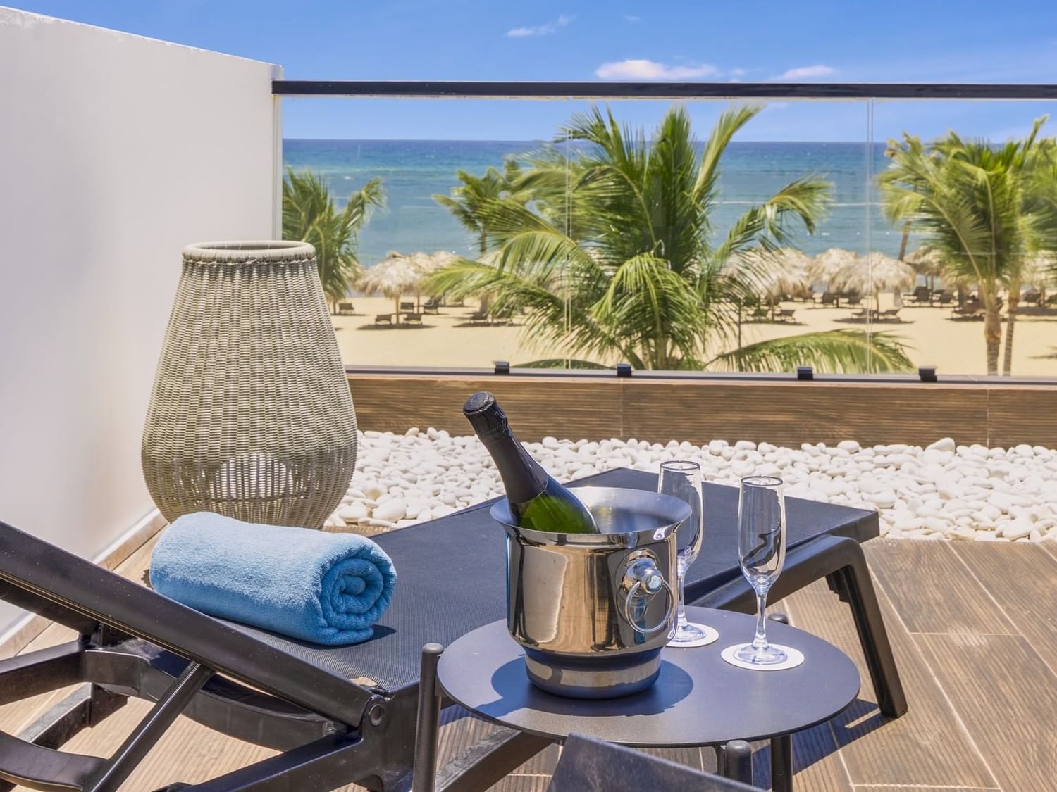 Champagne bottle and glasses arranged on table by lounger in a balcony overlooking the sea at Live Aqua Punta Cana