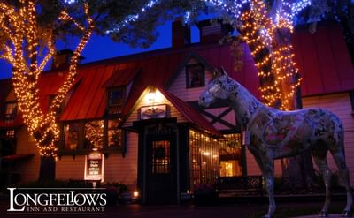 Exterior of restaurant at dusk. Trees are lit, and there's a hor