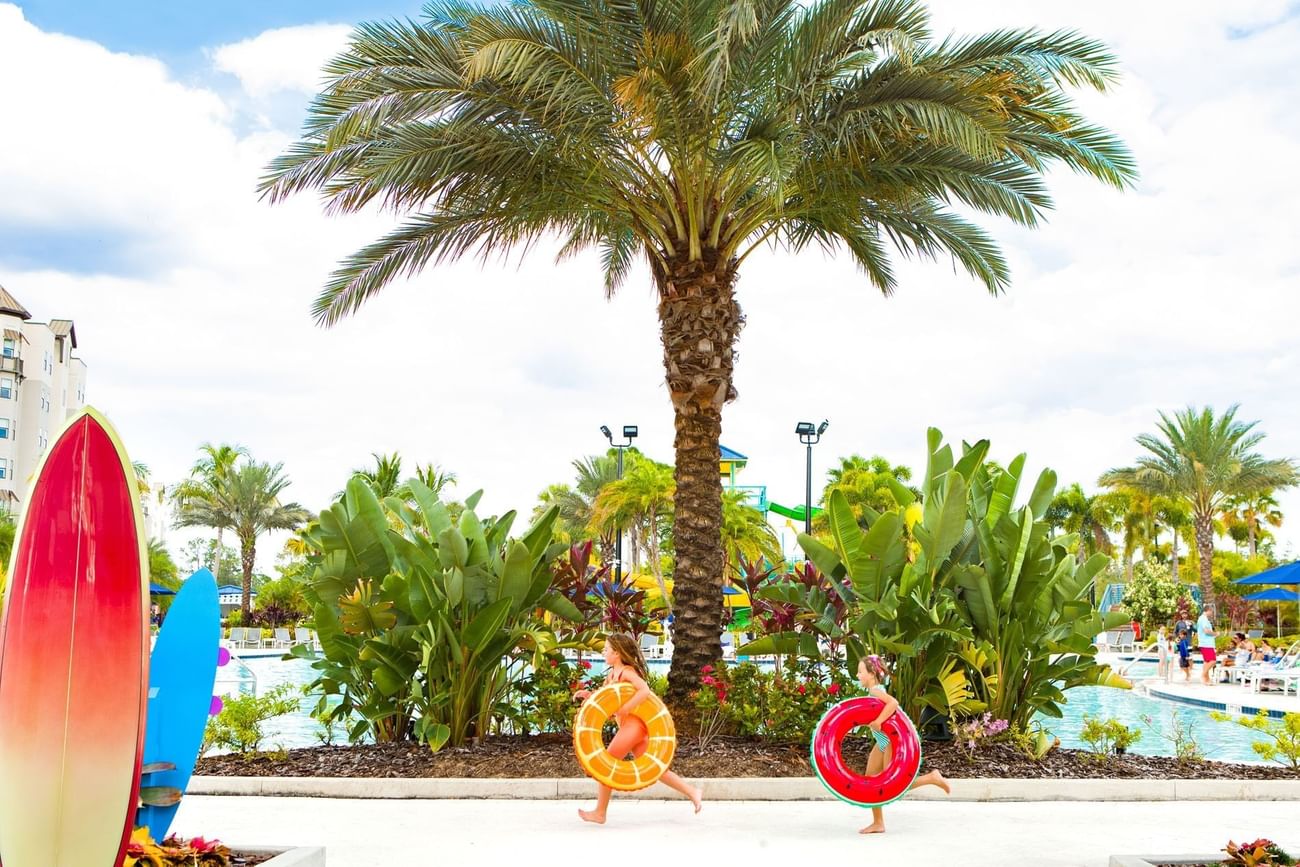 Two girls running with pool floats on a sunny day at Surfari Water Park Resort