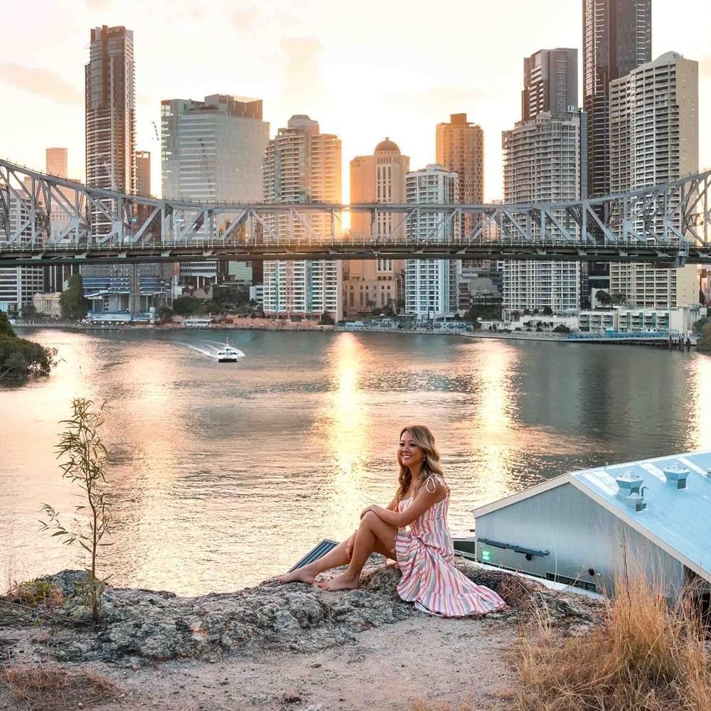 Woman sitting near Story Bridge and posing for a picture near Sofitel Brisbane Central