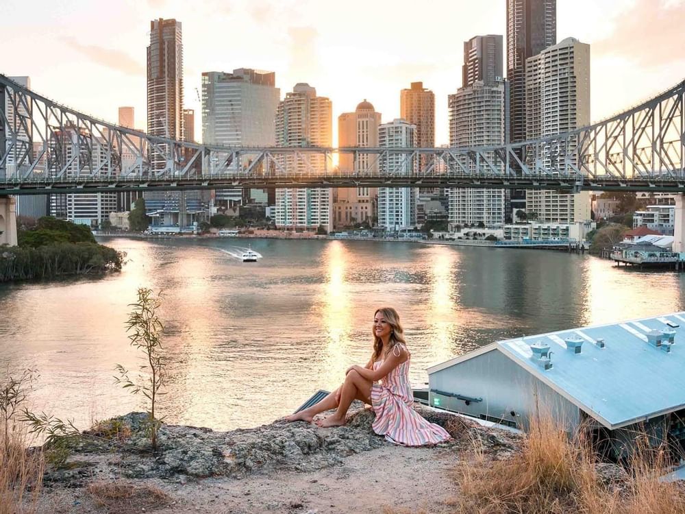 Woman sitting near Story Bridge and posing for a picture near Sofitel Brisbane Central