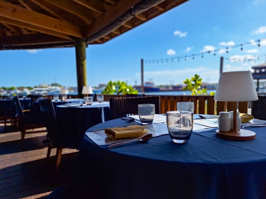 Set dining table by a small lamp and yellow napkins under a shaded patio at Warwick Paradise Island Bahamas
