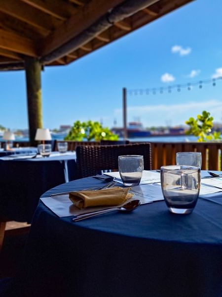 Dining tables under a wooden pavilion by a scenic waterfront in Edgewater Grill at Warwick Paradise Island Bahamas