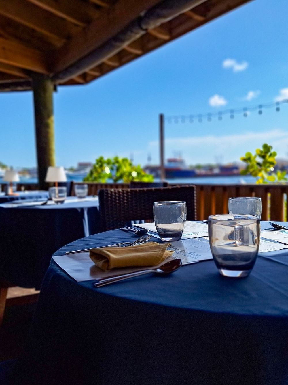 Dining tables under a wooden pavilion by a scenic waterfront in Edgewater Grill at Warwick Paradise Island Bahamas