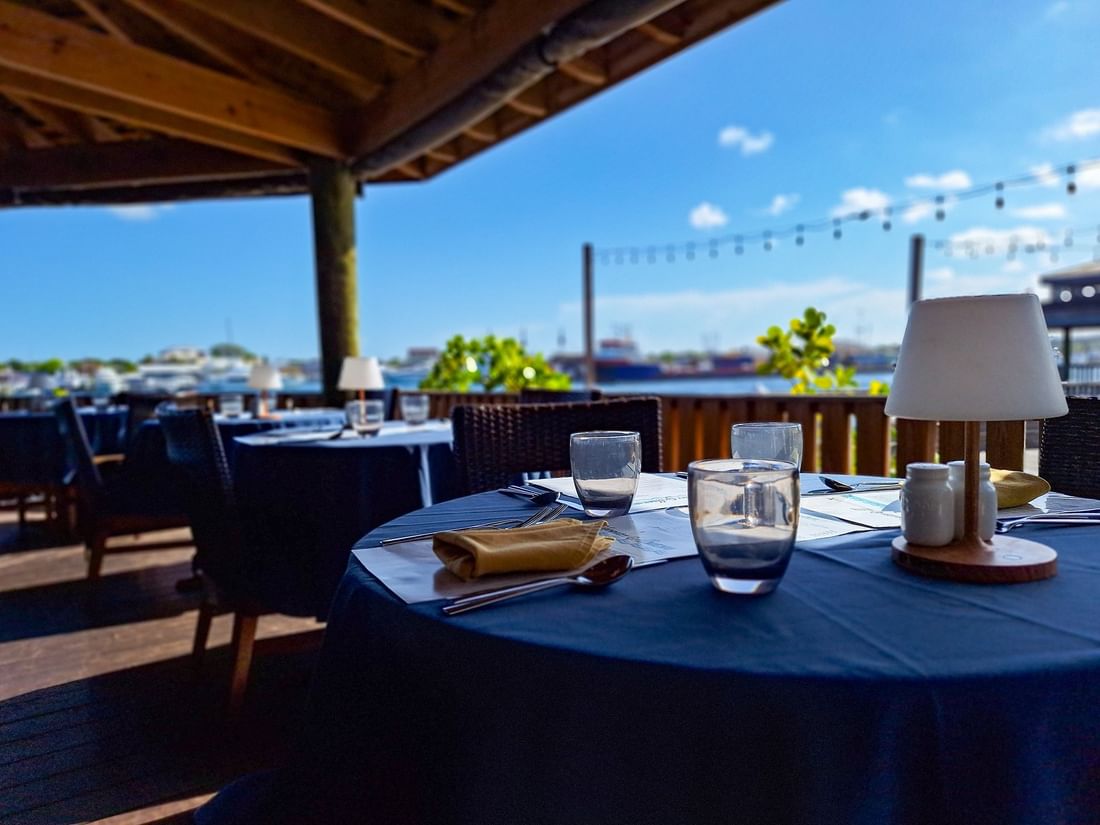 Dining tables under a wooden pavilion by a scenic waterfront in Edgewater Grill at Warwick Paradise Island Bahamas
