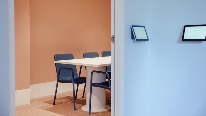 Modern study area with four chairs, a table, and two wall-mounted tablets.