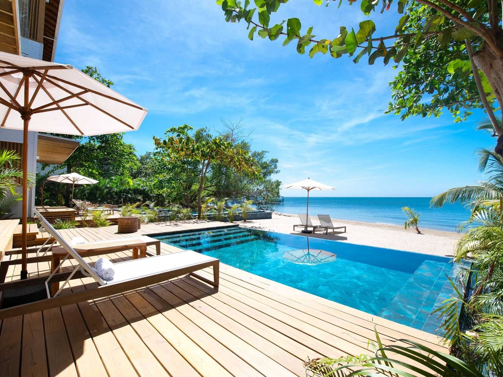 Ibagari Home Ocean & Tropical View Suites featuring outdoor wooden deck with lounge beds and a pool at Ibagari Hotel