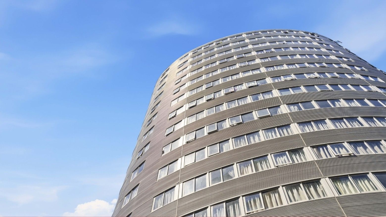 Tall building with many windows and a modern design under a clear blue sky.