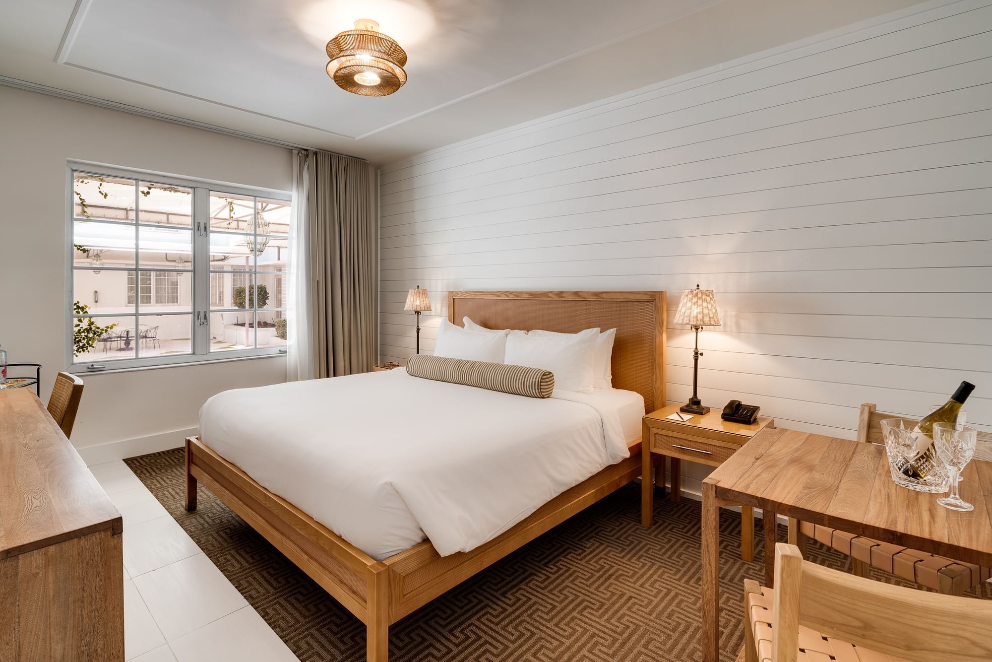 A hotel room with a king-sized bed, desk, and window